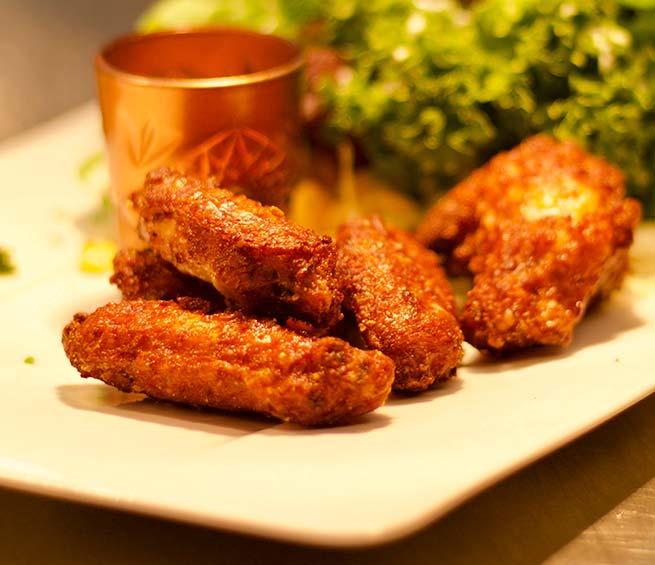 A plate of chicken wings with dip and salad on a plate.